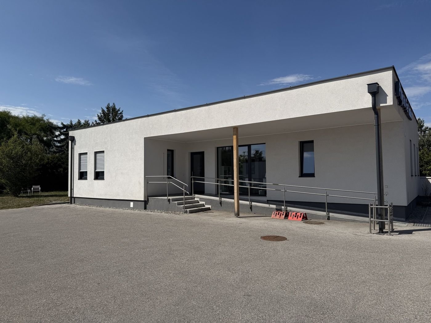 Eingang der Praxis mit Rampe, Handläufen und Stufen